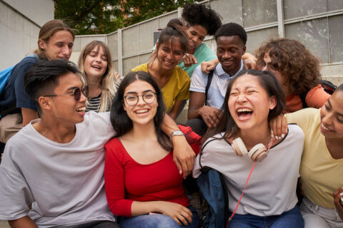 Diverse group of young people smiling together, representing community engagement, inclusion, teamwork, youth development, and social support programs.